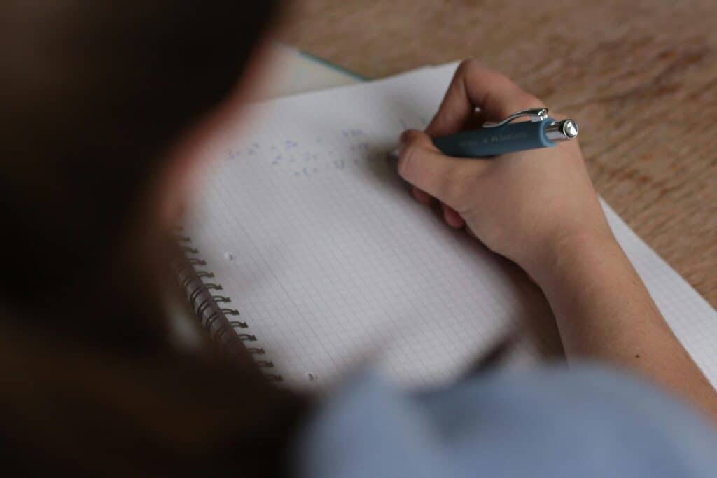 Pessoa estudando com caderno quadriculado e caneta, representando a preparação para a prova da certificação Susep.